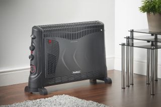 Left angled view of a black VonHaus convector heater standing on floor